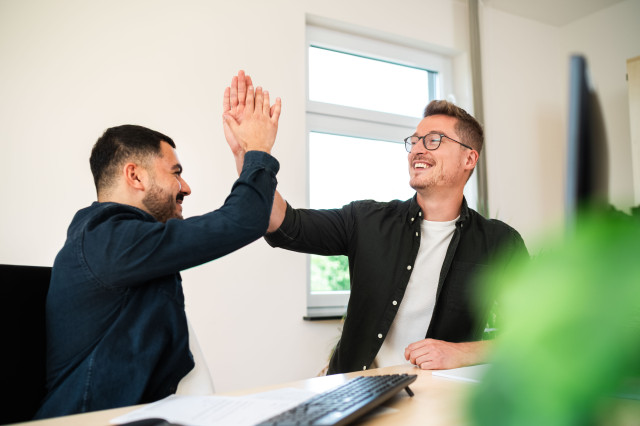 zwei Männer geben sich einen Handshake und lächeln