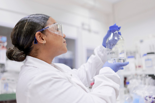 Lateinamerikanische Forscherin beobachtet in einem pharmazeutischen Labor den Inhalt eines Fläschchens