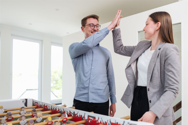 Zwei lachende Kollegen klatschen ein.