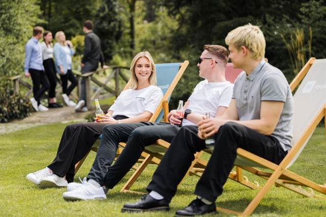 Teammitglieder sitzen zusammen in Liegestühlen und unterhalten sich.